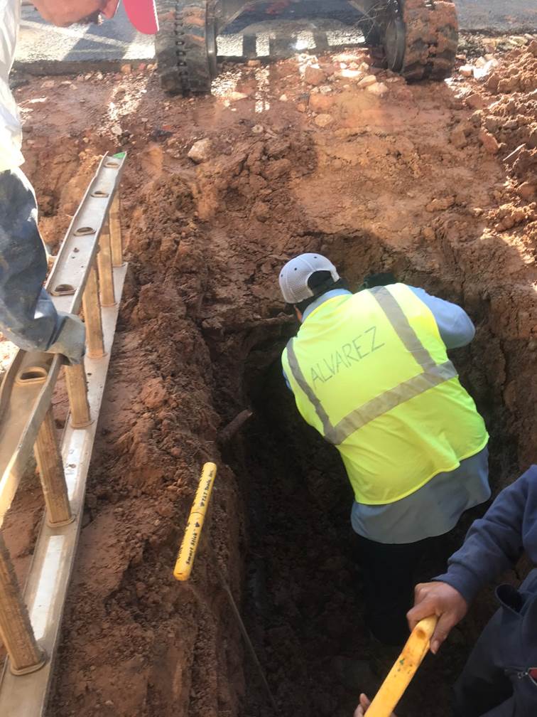 A group of men working in a hole

Description automatically generated