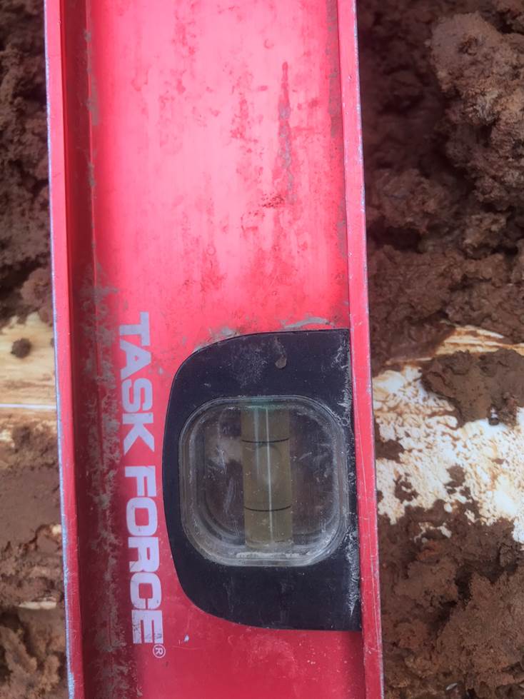 A red rectangular level on dirt

Description automatically generated